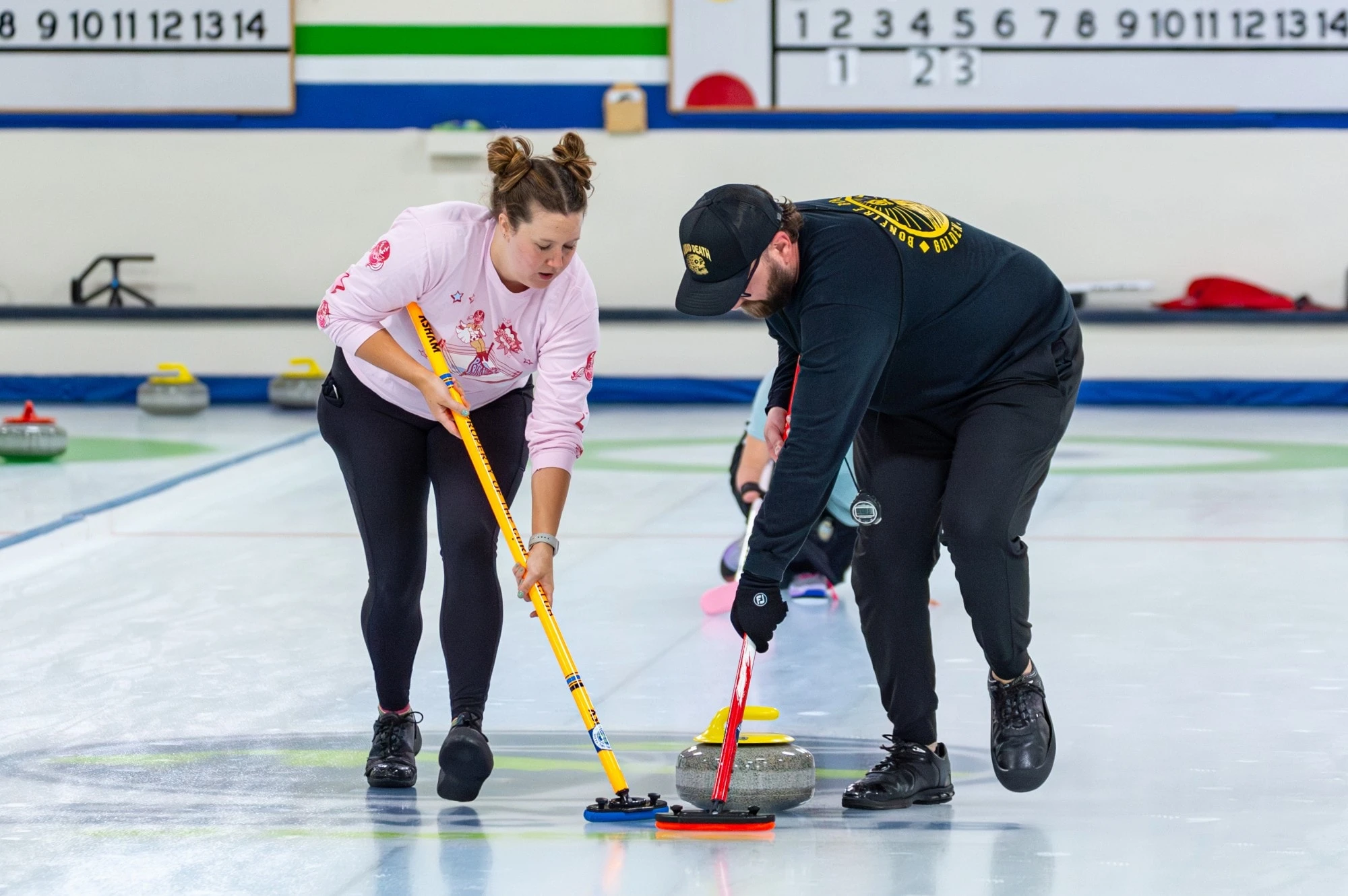Drew sweeping a curling stone down the ice alongside a teammate.