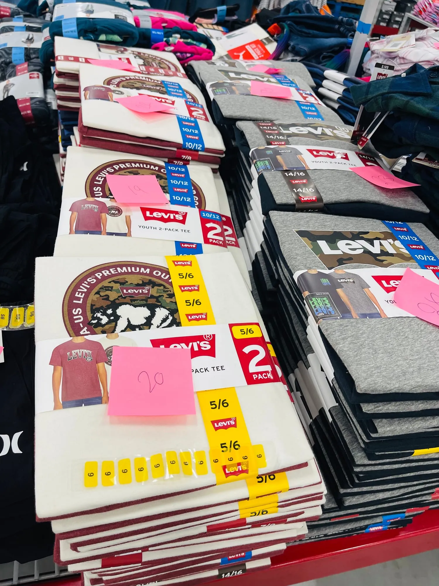 Folded Levi’s t-shirts on a table, covered in pink and yellow sticky notes with counts.