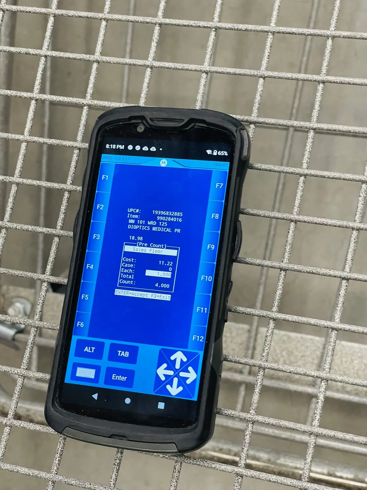 A rugged handheld scanner showing a dense blue text-only inventory screen.