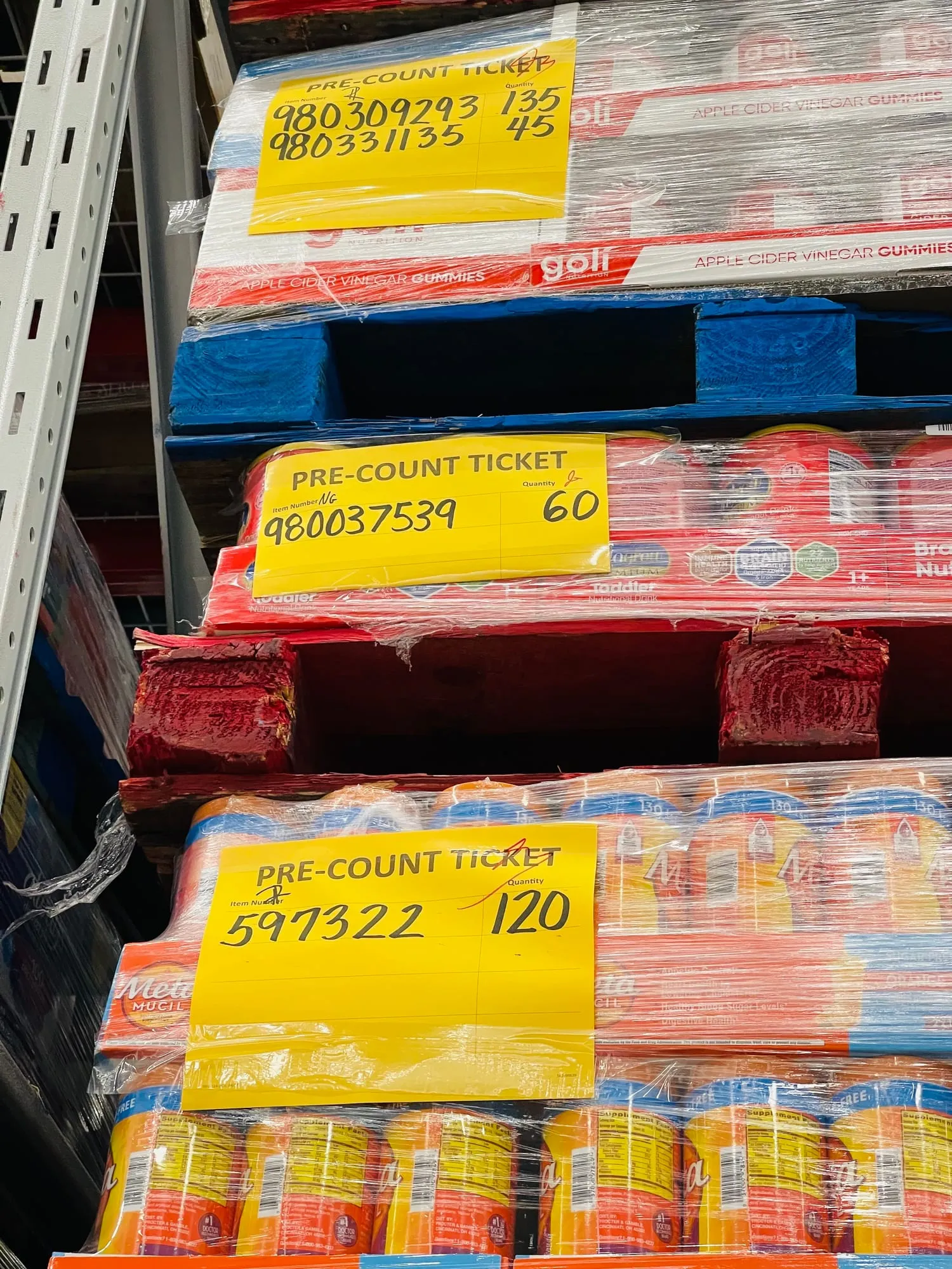 Pallets of soda with handwritten yellow precount tickets taped to the shrink wrap.